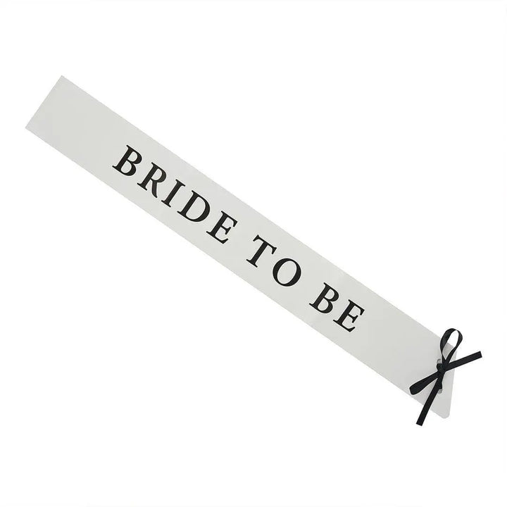 White Bride To Be Paper Sash - She’s Tying The Knot Hen Party Accessory - Coquette Bridal Shower Sash with Black Satin Ribbon - Hen Do Sash - Jolie Fete UK